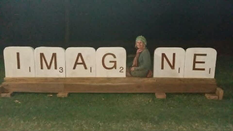 A club member with giant letter tiles spelling IMAGINE on Magnetic Island